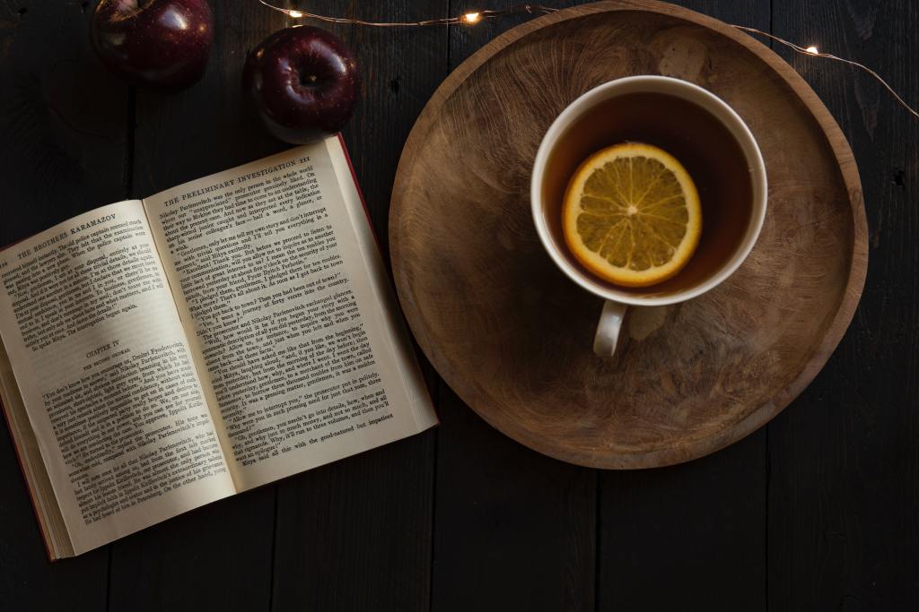 Photograph - an open book and a cup of black tea with lemon.